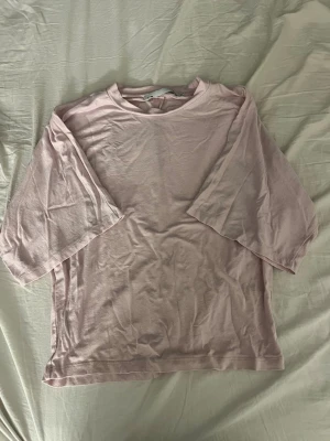 Ljusrosa t-shirt - En enkel och stilren ljusrosa t-shirt, den har rund halsringning och lite längre, lösa ärmar. Tröjan sitter tajtare vid magen & midjan medans ärmarna är mer lösa. Storlek M mens känns mer som S