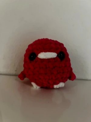 Virkat rött gosedjur - Säljer en handvirkad liten anka i rosa garn (ser röd ut på bilden) med vita detaljer på näbb och fötter samt svarta ögon. Perfekt present till någon som du gillar eller till dig själv. Materialet är mjukt, 8 cm hög och 6 cm bred. Pris går att diskutera. 