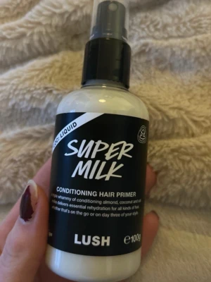 LUSH Super Milk Conditioning Hair Primer - Super Milk Conditioning Hair Primer från LUSH är en leave-in spray för håret med mandel-, kokos- och havremjölk. Flaskan är vit med svart etikett och spraymunstycke. Innehåller 100g och passar alla hårtyper för extra återfuktning och vård.