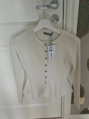 Vit kofta från Gina Tricot XS - Supersöt vit kofta från Gina Tricot med rund halsringning och knappar framtill. Modellen har en lätt utsvängd midja och långa ärmar. Perfekt att styla med jeans eller kjol för en trendig look.