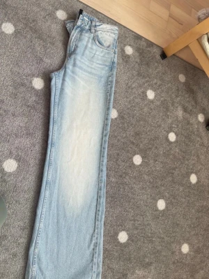 Ljusblå raka jeans från H&M - Säljer ett par ljusblå jeans med rak passform och klassisk femficksdesign. Jeansen har en snygg tvättad look med ljusare partier framtill och är tillverkade i denim. Mjuka och sköna men för små för mig.Perfekta för en avslappnad och trendig stil.