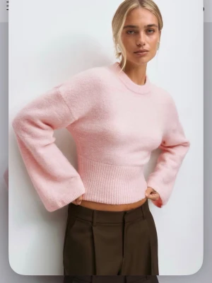 Ljusrosa stickad figursydd tröja - Ljusrosa stickad tröja från Gina med breda ärmar och ribbad figurnära nederkant. Materialet är mjukt och fluffigt, och sitter jättefint på kroppen!