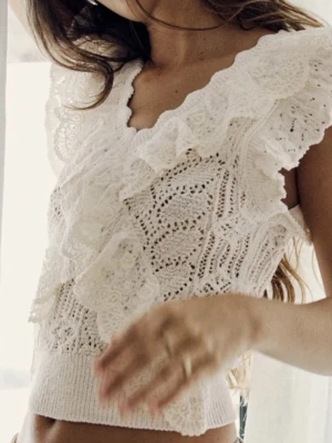 Vit spets topp med volangdetaljer - Supersöt vit topp i spets med v-ringning och breda volangdetaljer framtill och vid axlarna