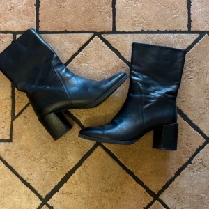 Filippa K, boots med klack - Snygga svarta stövletter i skinn med bred klack från Filippa K.  Skorna har ett minimalistiskt uttryck och når till halva vaden. 