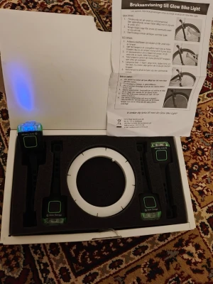 Glow Garage cykelbelysning kit - Säljer ett Glow Garage cykelbelysning kit med LED-ljus. Kitet innehåller fyra svarta lampor med blåa ljus och ett vitt ringformat ljus reflekterande tejp , allt i originalförpackning. Perfekt för att synas bättre på cykeln. Instruktionsblad medföljer.