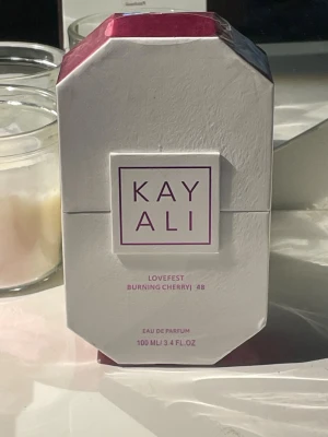 Kayali Lovefest Burning Cherry 48 EdP - Kayali Lovefest Burning Cherry 48 är en Eau de Parfum i en lyxig, mörkröd glasflaska med kristallin kork. Doften har en söt och fruktig karaktär med tydliga körsbärstoner, inslag av trä och karamell. Flaskan rymmer 100 ml och har en modern, elegant design.