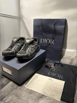 Svarta Dior B30 sneakers - Snygga svarta Dior sneakers med silver detaljer. Hel ny med box, 2 påsar, extra par skodnöre och metall grej. Storlek 44 (passar bra även för 43).