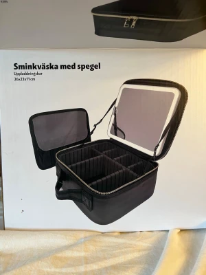 Svart sminkväska med spegel -  Sminkväska med spegel och belysning Form Living, Storlek: 26x23x11cm, Material: Glas, Plast ABS, textil, Uppladdningsbar USB C kabel ingår, 3 ljusinställningar, Justerbara fack. Den avtagbara spegeln gör sminkningen bekväm oavsett var du befinner dig. Med den inbyggda belysningen har du alltid bra ljus, oavsett var du är..