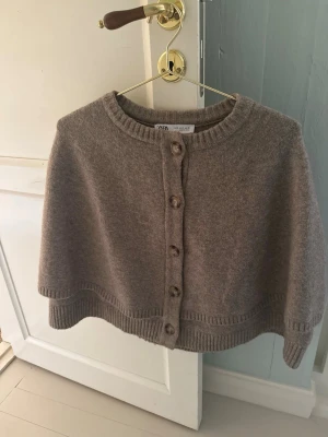 Beige/brun stickad cape/kofta från Zara - Säljer den slutsålda skit snygga koftan/cape från Zara. Så mysig och perfekt nu i mellanvädret.