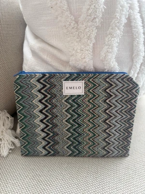 Mönstrad necessär från Emelo - Säljer en snygg necessär från Emelo med zigzag-mönster i grönt, svart, vitt och blått. Väskan har en blå dragkedja och är tillverkad i ett tygmaterial. Perfekt för att förvara smink, småprylar eller andra viktiga saker i väskan. Mått ca 20x15 cm