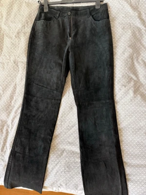 Svarta läderbyxor med raka ben - Snygga svarta byxor i mjuk läder med raka ben och klassisk femficksmodell. Byxorna har knapp- och dragkedjestängning samt sömdetaljer över knäna. Perfekta för dig som vill ha en stilren och trendig look. Size 40 dam