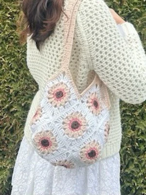 Virkad shoppingväska med blommor - Unik handgjord shoppingväska i virkat material med vita, beige och rosa toner. Väskan har ett blommigt mönster med solrosliknande motiv och breda axelband. Perfekt för dig som gillar boho-stil och vill ha en personlig accessoar.