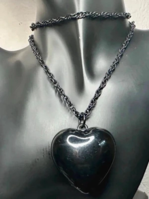 Svart halsband med hjärthänge - Statement-halsband från 90-talet Y2K-stil med stort svart hjärta och kraftig kedja. Blank finish som ger ett tydligt uttryck – perfekt till alt, grunge eller edgy outfits. Kan bäras både långt eller dubbelvarvat.  Kedja ca 80 cm, hänge ca 5 x 4 cm. Bra vintage-skick med lätt ytslitage.  Priset är redan lågt så jag prutar inte, men erbjuder bra rabatt vid köp av flera saker. Rensar garderob – kolla gärna mina andra annonser!  TAGGAR: y2k, halsband, heart necklace, svart, goth, grunge, altstyle, s