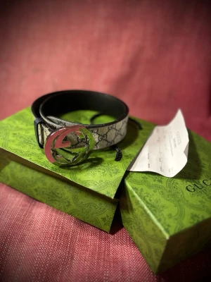 Gucci GG bälte med silverdetalj - Snyggt Gucci GG Supreme bälte i beige och grått med klassiskt monogrammönster och stor silverfärgad GG-logga som spänne. Bältet är gjort i canvas med läderdetaljer och kommer i originalförpackning med grön Gucci-box och påse därmed kvitto! Skick som nytt och bältet är använt ett fåtal gånger.