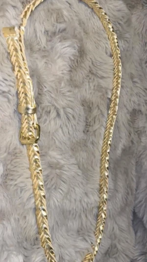 Flätat guldigt bälte - Snyggt flätat bälte i guldig färg med metallspänne. Perfekt accessoar för att lyfta vilken outfit som helst. Bältet har en smal design och ger en trendig touch till din stil.