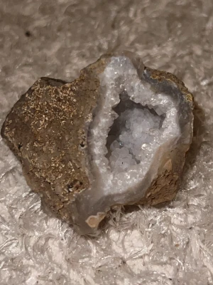 Geod med vita kristaller - Säljer en naturlig geod med gnistrande vita kristaller inuti och brun, ojämn yta på utsidan. Perfekt som dekoration eller samlarobjekt. Kristallerna har en glittrande effekt och stenen har en unik, organisk form.