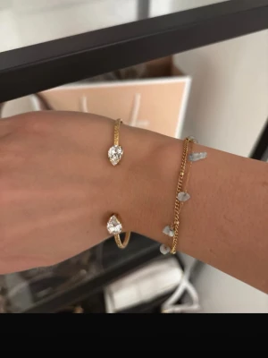 Guldarmband med pärldetaljer - Snyggt armband i guldton med små vita pärlor och en tunn kedja. Armbandet har en trendig och stilren design som passar perfekt till flera olika looks. Pärldetaljerna ger en extra touch av elegans och armbandet är lätt att matcha med andra smycken.