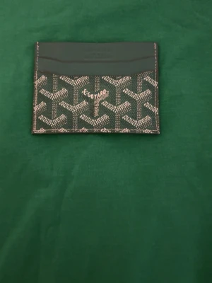 Grönt kortfodral  - Snyggt grönt  kortfodral  med det klassiska vita och gråa mönstret. Fodralet har flera fack för kort och är tillverkat i slitstarkt material med exklusiv känsla. Perfekt för dig som vill ha en stilren och lyxig accessoar.