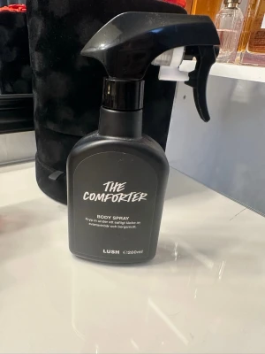 Lush The Comforter Body Spray - The Comforter Body Spray från Lush i en svart sprayflaska på 200 ml. Doften har inslag av svartvinbär och bergamott.  Har endast använts fåtals gånger