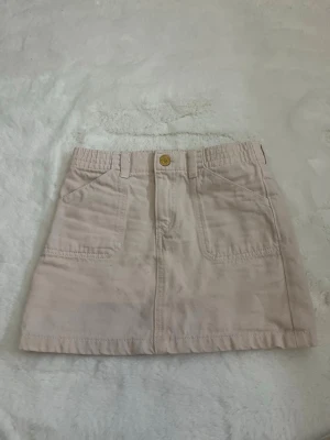 Beige kortkjol i manchester - Snygg beige kortkjol i mjuk manchester med fickor fram och bak samt knapp och hällor i midjan. Perfekt att styla med en enkel topp eller hoodie för en chill look.