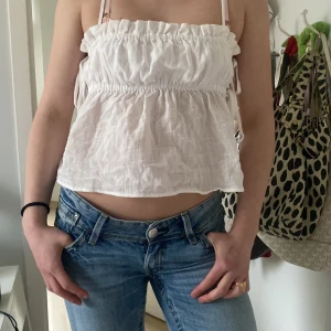 Vit linnetopp med knyt Nelly - Söt vit linnetopp med smala axelband och knyt i sidorna. Helt ny med lapparna på, aldrig använd, endast testad🥰