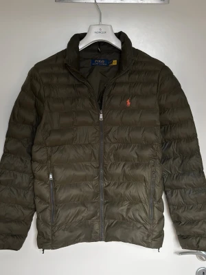 Olivgrön pufferjacka från Polo Ralph Lauren - Polo Ralph Lauren The Golden Packable Jacket. I nyskick utan defekt. Storlek S. Vanliga nypris är ca 4200 kr men finns nu på nätet med rabatt för 2600 kr. Skickar alltid samma dag eller nästa dag. Skriv för mer information eller frågor. 
