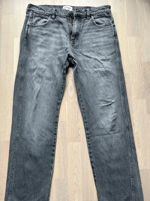 Wrangler 880 frontier jeans - relaxed straight W32 L32 - Dessa grå relaxed straight-jeansen från Wrangler är använda ett fåtal gånger utan tecken på slitage. Modellen har en medvetet sliten look med fransad fåll. Raka ben i en avslappnad passform. Storlek: W32 L32