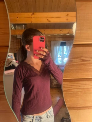 Vinröd tröja, Gina Tricot Young - Snygg vinröd  långärmad topp med v-ringning och spetsdetaljer vid halsringningen och ärmsluten. Perfekt att styla med jeans eller kjol för en trendig look.