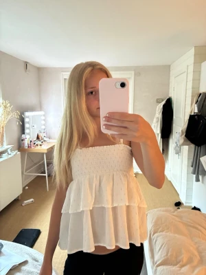 Vit volang linnetopp  - Supersöt vit linnetopp med smock upptill och tunna axelband som går att ta av. Toppen har två lager volanger som ger en luftig och flowy känsla. Perfekt för varma dagar och enkel att styla med jeans eller kjol. Väl använd men ändå bra skick, dock har tyget som banden sitter fast i börjat lossna så har sytt om de. Priset går att diskutera.