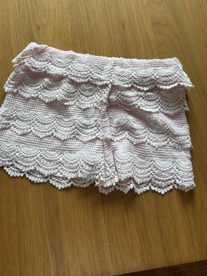 Ljusrosa spets-shorts från Kappahl - Supersöta ljusrosa shorts från Kappahl med vacker spets och vågig kant. Perfekta för dig som vill ha en romantisk och feminin stil. Shortsen har elastisk midja och är fodrade för extra komfort.