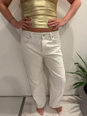 Vita baggy jeans från Zara  - Säljer ett par vita jeans med rak passform och låg midja. Klassisk femficksmodell och knappgylf. Jeansen är i ett tjockare denimtyg och har en clean look utan slitningar eller detaljer.OBS!! Storlek 42 men sitter som en M då de är små i storleken. 