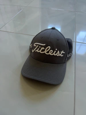 Mörkgrå Titleist keps - Riktigt snygg Titeist keps! Skick 9/10. Andningsbart material som funkar perfekt på en varm sommar dag. Bara o skriva om ni har funderingar!👊