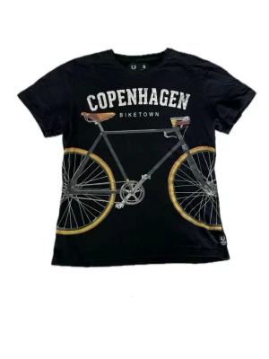 Svart t-shirt med cykeltryck - Cool svart t-shirt med stort cykeltryck och texten 'Copenhagen Biketown' på bröstet. Klassisk passform och rund hals. Storlek S.