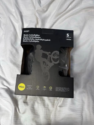 Svart skate- och cykelhjälm junior - Säljer en svart skate- och cykelhjälm från Biltema med MIPS-teknologi för extra säkerhet. Hjälmen är i storlek S (50-55 cm) och passar juniorer. Perfekt för både skate och cykling, med modern design och skyddande material.