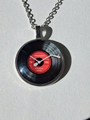 Halsband LP-SKIVA I 2D Retro mode  - Silvrigt halsband med svart, vit och röd LP-SKIVA I 2D Retro mode. Samt text och detaljer. Materialet rostfritt stål 