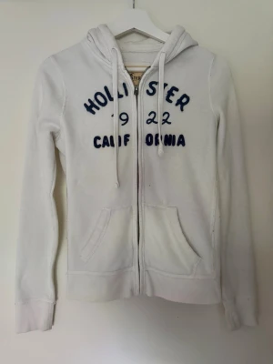 Zip up Hoodie Hollister  - Vit zip up Hoodie ifrån Hollister, har två fläckar de bilderna!