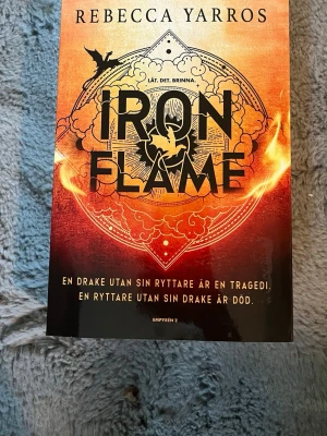 Iron Flame av Rebecca Yarros - Iron Flame av Rebecca Yarros är en fantasyroman med ett eldfärgat omslag och drakmotiv. Boken handlar om drakryttare, farliga utmaningar och hemligheter på en brutal skola. Perfekt för dig som gillar spänning, magi och episka äventyr.