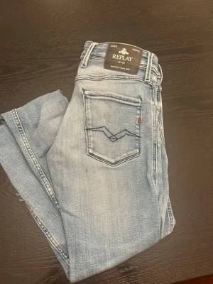 Ljusblå slim fit Anbass jeans från Replay - Snygga ljusblå jeans från Replay i modellen Anbass. Jeansen har slim fit passform, klassisk femficksdesign och coola slitningar. Tydliga sömmar och Replay-logga på fickan ger extra stilpoäng. Perfekta till en avslappnad look.