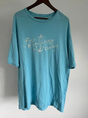 Polo Ralph Lauren Graphic T-shirt - Polo Ralph Lauren Graphic T-shirt Storlek: L Passform: Relaxed Fit Krage: Rund hals Material: Bomull Mått: Bröstvidd 116 cm, längd 72 cm, axel 56 cm Skick: Denna T-shirt är i ett väldigt fint skick utan defekter  Nypris cirka: 800 kr