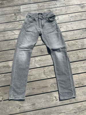 Grå raka jeans från Replay, stl 14A-158/164 - Snygga grå jeans från Replay med rak passform och klassisk femficksdesign. Jeansen har en tvättad look och är tillverkade i ett mjukt denimtyg som ger en avslappnad vibe. Perfekta till sneakers och hoodie för en chill stil.