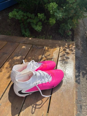 Nike rosa och vita fotbollsskor - Säljer ett par helt nya Nike phantom rosa fotbolls skor high cut, skorna är använda 2 gånger. Säljer pågrund utav att jag själv tyckte att skorna var förstora för mig. Köpte för 1000kr säljer för 700kr då dem bara är använda 2 gånger innan. Pris kan diskuteras 