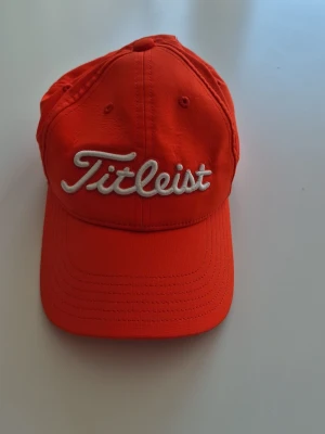  Titleist keps med broderad logga - Snygg keps från Titleist med vit broderad logga framtill. Klassisk böjd skärm och justerbar baksida. Tillverkad i ett lätt och bekvämt material som passar perfekt för golf eller andra utomhusaktiviteter.