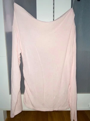 Ljusrosa offshoulder långärmad topp - Säljer en ljusrosa långärmad topp med offshoulder-design. Toppen är enkel och stilren, tillverkad i mjukt bomullsliknande material. Perfekt för dig som gillar en avslappnad men trendig look.