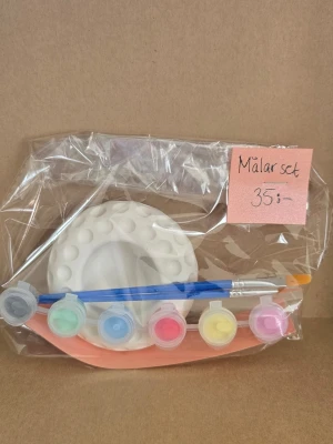 Målarset med färger och pensel - Ett komplett målarset med en vit gipsskål, färger och penslarl. Perfekt för kreativa projekt och pyssel. Allt är förpackat i en genomskinlig plastpåse.