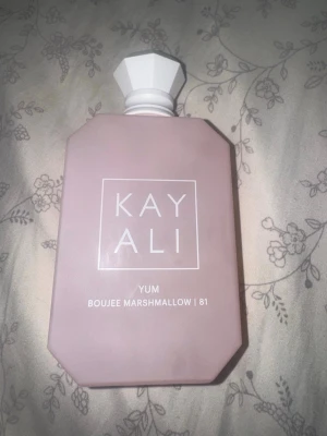 Kayali Yum Boujee Marshmallow parfym - Kayali Yum Boujee Marshmallow 81 är en parfym i en matt ljusrosa flaska med vit, multifasetterad kork. Flaskan har en modern, kantig design och tydlig vit text på framsidan. Doften är känd för sina söta och gourmanda toner. Den är 100 ml nypris 1539 köpt på Sephora 
