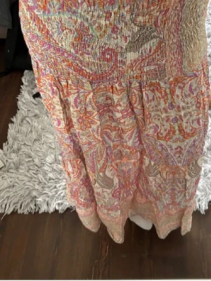 Långkjol med blommigt mönster - Luftig långkjol med blommigt mönster. Kjolen har smockad midja och volangdetalj nedtill. Perfekt för sommaren. Köpt på quinte för 599kr för 2 år sen och är fortfarande i bra kvalitet.