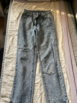 Acid wash raka jeans - Säljer ett par snygga acid wash jeans med rak passform och hög midja. Jeansen har klassiska fem fickor och dragkedja med knapp. Perfekta för dig som gillar en retro och avslappnad stil.