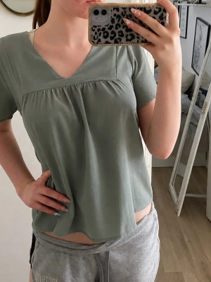 Grön kortärmad blus med v-ringning - Fin mintgrön blus med v-ringad hals och korta ärmar. Blusen har en lös passform och ett enkelt, stilrent uttryck. Perfekt till jeans eller kjol. Helt oanvänd💕
