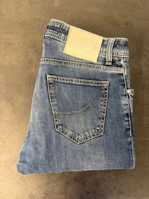 Jacob Cohën 622 Comfort, stl 32 - Säljer ett par ljusblå jeans från Jacob Cohen med raka ben och klassisk femficksmodell. Jeansen har en snygg tvättad look och kontrastsömmar. Materialet är mjukt denim som känns bekvämt och passar till många olika stilar.