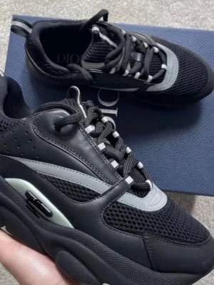 Svarta chunky sneakers med grå detaljer - Snygga chunky sneakers i svart med grå detaljer och meshpaneler för extra ventilation. Skorna har en sportig vibe med tjock sula och coola kontrastdetaljer. Perfekta för dig som gillar streetwear och vill sticka ut.